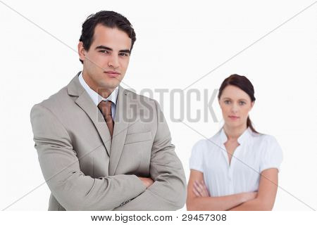 Salesman with arms crossed and colleague behind him against a white background