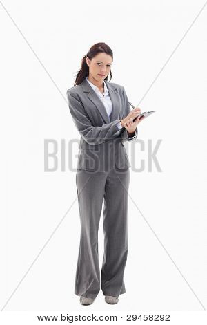 Businesswoman writing on a clipboard against white background