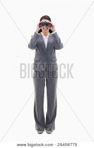 Businesswoman smiling and looking through binoculars against white background