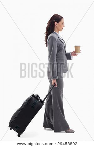Profile of a businesswoman with a suitcase and holding a coffee against white background