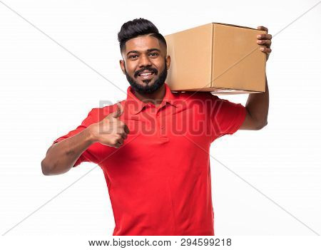 Smiling Delivery Man In Blue Uniform Carrying Packages While Gesturing Thumb Up Sign Isolated On Whi