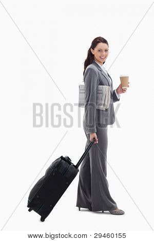 Profile of a businesswoman smiling with a suitcase, a newspaper and a coffee against white background