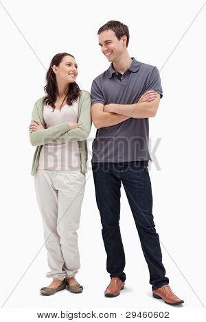 Couple with a complicit smile while crossing their arms against white background