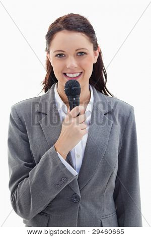 Close-up of a businesswoman smiling and holding a microphone against white background