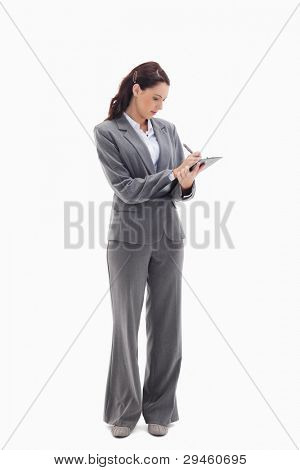 Businesswoman focusing and writing on a clipboard against white background