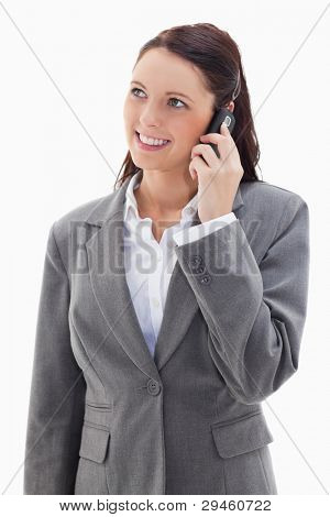 Businesswoman looking up while smiling on the phone against white background
