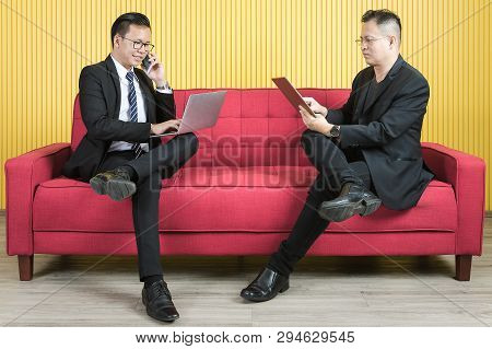 Young And Middle Aged Asian Businessmen Wearing Eyeglasses In Dark Suit, Both Busily Checking Data F