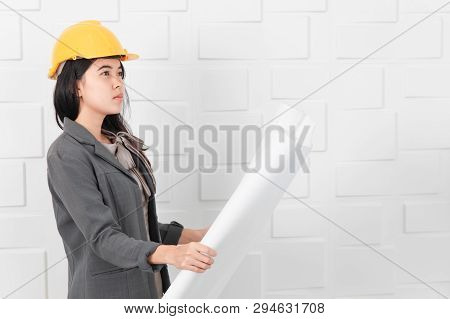 Shot Of Young Beautiful Asian Architect In Business Casual, Wearing Yellow Hardhat Holding And Reche