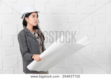 Shot Of Young Beautiful Asian Architect In Business Casual, Wearing Yellow Hardhat Holding And Reche