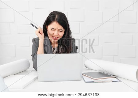 Shot Of Young Beautiful Asian Architect In Business Casual, Pen In Hand Looking At Laptop Screen, Re