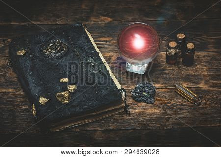 Crystal Ball And A Magic Book On A Wizard Table Background.