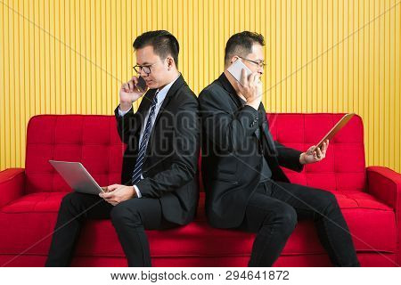 Young And Middle Aged Asian Businessmen Wearing Eyeglasses In Dark Suit, Both Busily Checking Data F