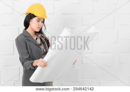 Shot Of Young Beautiful Asian Architect In Business Casual, Wearing Yellow Hardhat Holding And Reche