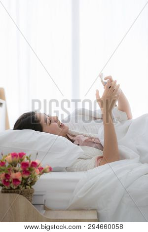 Young And Beautiful Asian Woman Sleep In Bed And Using Smartphone After Awake With Copy Space On Top