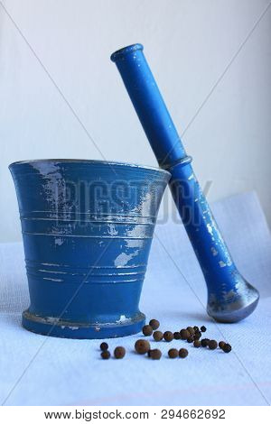 Black Peppercorns And Allspice In Ancient Metal Mortar With Pestle On Linen Background