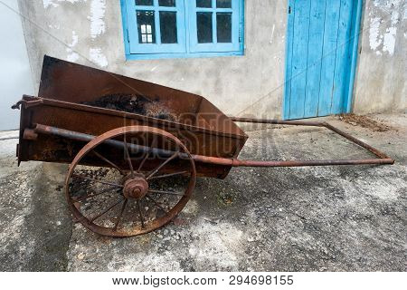 Old Farm Cart With Two Whells Standing Near House.