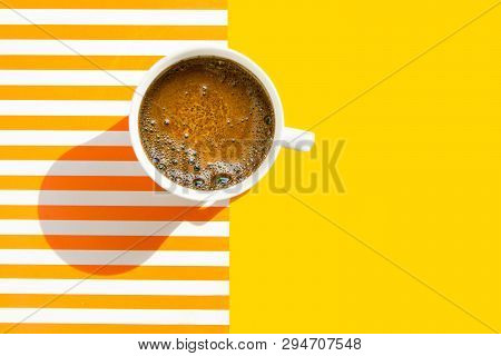 White Cup Of Freshly Brewed Coffee With Foamy Crema On Duotone Yellow White Striped Background. Top 