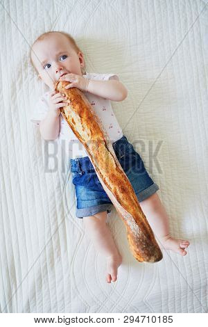 Six Months Old Baby Girl Eating Traditional French Bread (baguette). Introducing Solids To Infant Ki