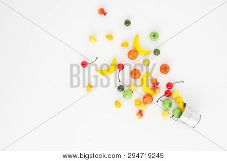 A Scattering Of Many Small Different Fruits On A White Background. Mini Copy Of A Metal Bucket. The 