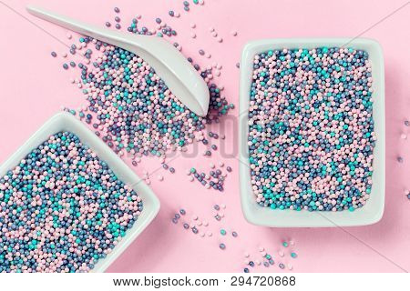 Colorful Nonpareils Cake Candy Sprinkles In Two White Rectangular Bowls And Spoon On Pink Background
