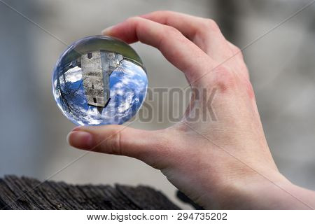 Crystal Lensball In Hand And Ancient Gothic Church Of All Saints Ludrova, Slovakia