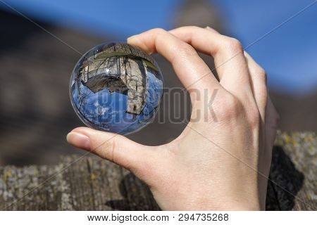 Crystal Lensball In Hand And Ancient Gothic Church Of All Saints Ludrova, Slovakia