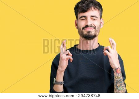 Young handsome man over isolated background smiling crossing fingers with hope and eyes closed. Luck and superstitious concept.