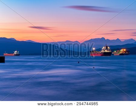 freighters stop at the bay of vancouver at sunset.