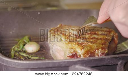 Unrecognizable Man Chefs Hands Using Two Forks Are Rotaring A Juicy Beef Steak Wich Roasting With Ro
