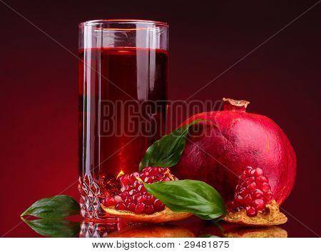 rijpe pomergranate en glas sap op rode achtergrond