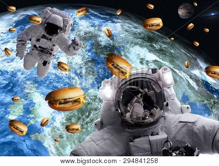 Astronauts In Outer Space With Cheseburgers On The Earth And Marts Planets On The Background. Scienc