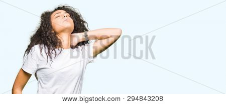 Young beautiful girl with curly hair wearing casual white t-shirt Suffering of neck ache injury, touching neck with hand, muscular pain