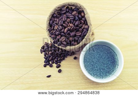 Sweet Basil In White Cup And Coffee Beans In Sack Sisal On Wooden Background.