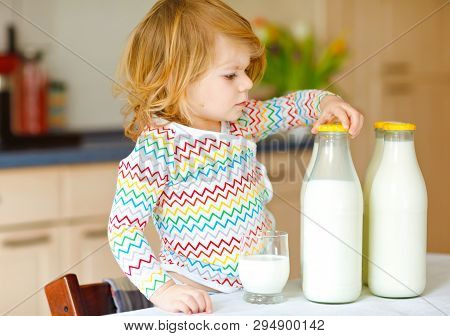 Adorable Toddler Girl Drinking Cow Milk For Breakfast. Cute Baby Daughter With Lots Of Bottles. Heal