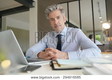 Handsome businessman in offiice looking at camera