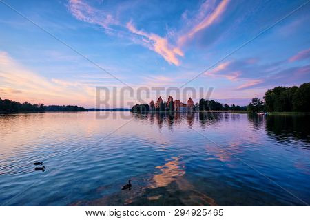 Trakai Island Castle in lake Galve, Lithuania on sunset with dramatic sky reflecting in water and ducks. Trakai Castle is one of major tourist attractions of Lituania