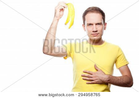 Disappointed And Hungry Handsome Guy Holding Banana Skin Over White Background