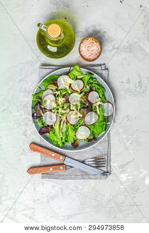 Salad With Radishes, Olive Oil, Pink Salt, Knife And Fork For Salad Over Gray Concrete Texture Backg