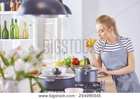 The Girl At The Table In The Kitchen With A Glass Of Orange Jui