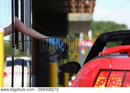 Hand In Protective Glove Holds Payment Terminal And Hands It To Driver In Car. Safe Service In Coron