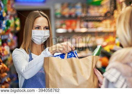Adult woman in medical mask picking up order in grocery store