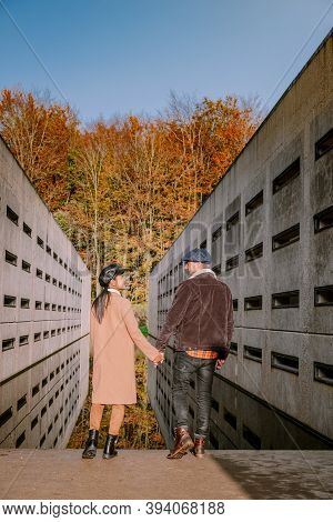 Couple Men And Woman Hiking In The Forest During Autumn And Small Streaming Water River With Fall Co