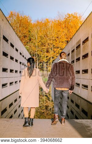 Couple Men And Woman Hiking In The Forest During Autumn And Small Streaming Water River With Fall Co