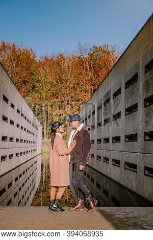 Couple Men And Woman Hiking In The Forest During Autumn And Small Streaming Water River With Fall Co