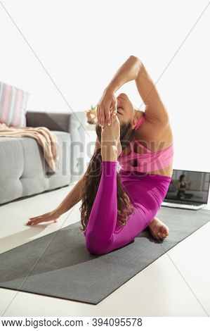 Inspired. Beautiful Young Woman Working Out Indoors, Doing Yoga Exercise On Gray Mat At Home. Long H