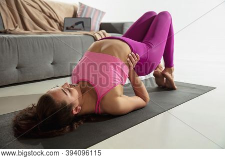 Strong. Beautiful Young Woman Working Out Indoors, Doing Yoga Exercise On Gray Mat At Home. Long Hai