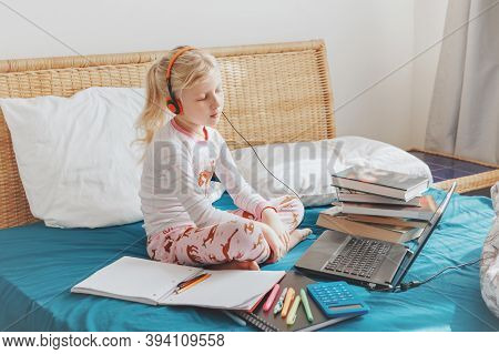 Caucasian Girl Child Sitting In Bed And Learning Online On Laptop Internet. Virtual Class Lesson Sch