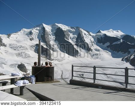 Against The Backdrop Of The Majestic Mountain Peaks, People Sit Relaxed In The Bath.