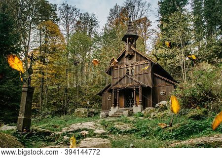 Old Wooden Pilgrimage Rural Chapel Of Virgin Mary, Cz: Stozecka Kaple And Iron Cross, Standing In A 