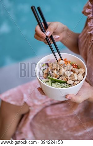 Woman Sitting By The Pool Against Blue Water Background With Chopsticks And Eating Takeout Healthy O